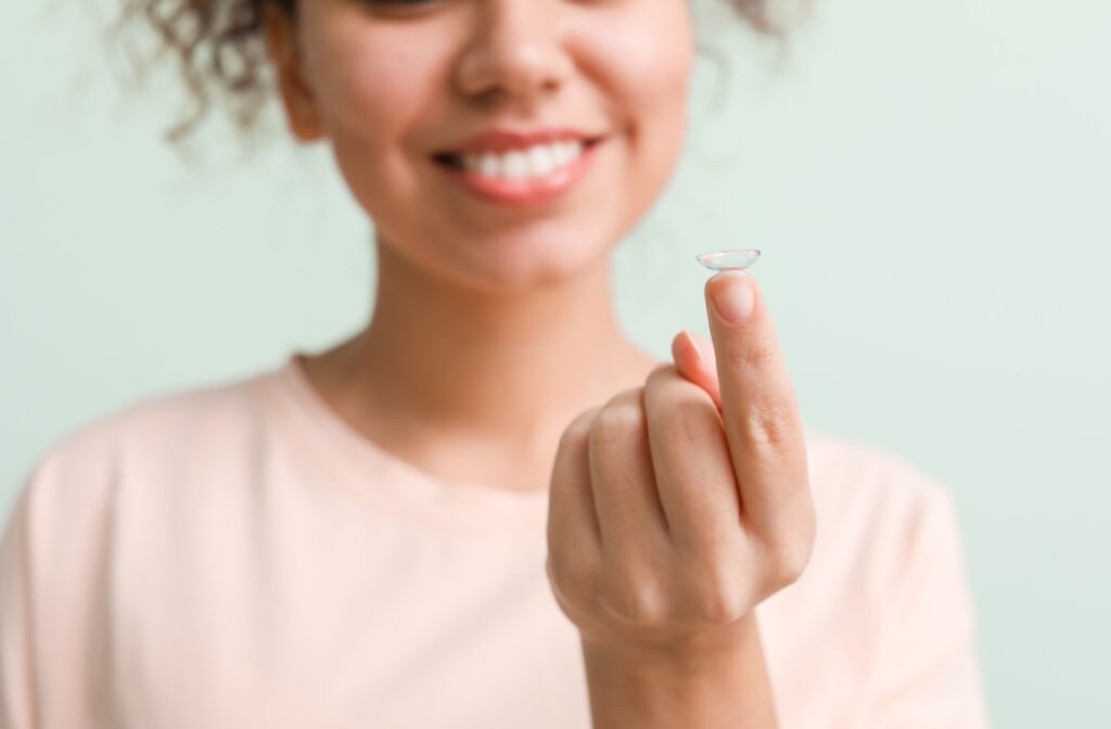 A person holds up a contact lens on their index finger.