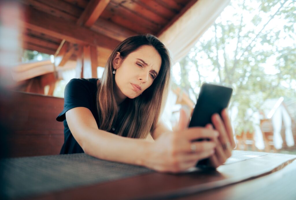 a woman struggling to see what's on her phone due to dry eye syndrome