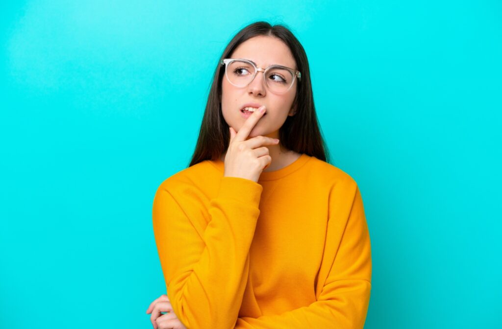 A person on a teal background wondering if their glasses are worsening their vision.