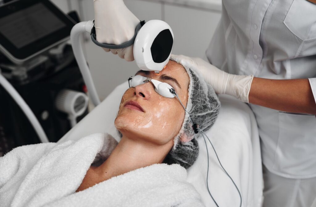 An optometrist carefully uses the IPL device around a patient's eyes for their dry eye treatment.