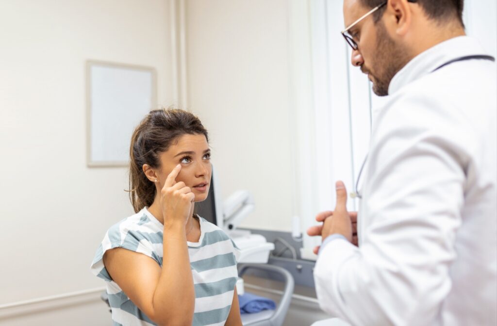 A patient points to their eye while talking to their optometrist about their dry eye symptoms.